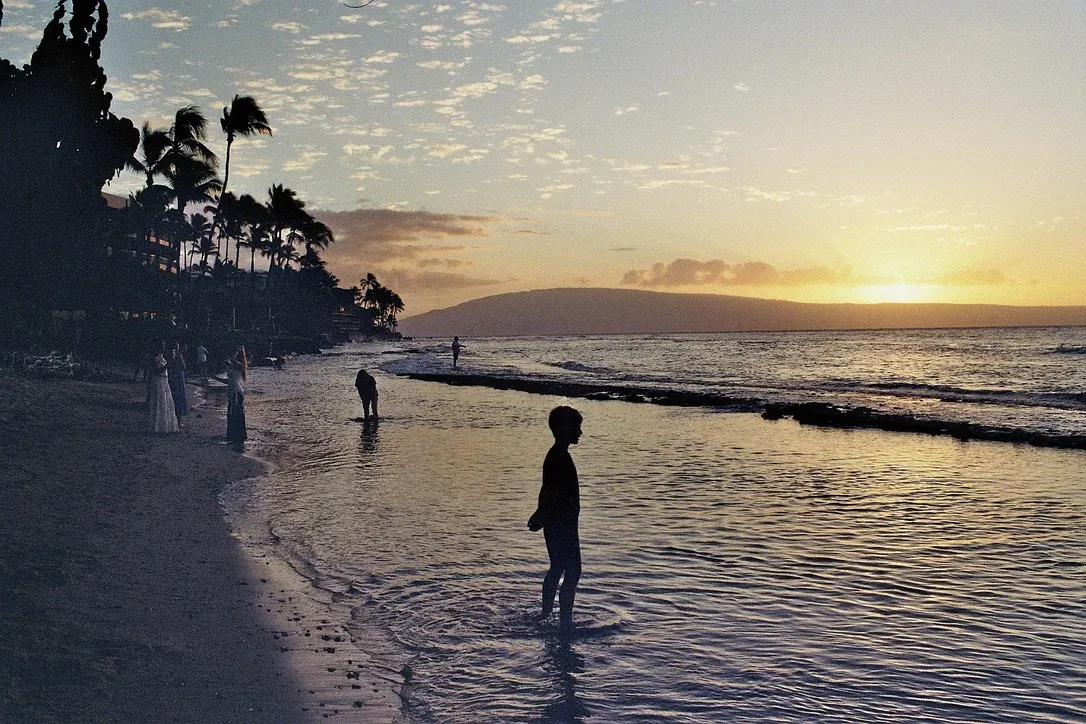 Tourists on Maui beach photographing sunset with smartphones