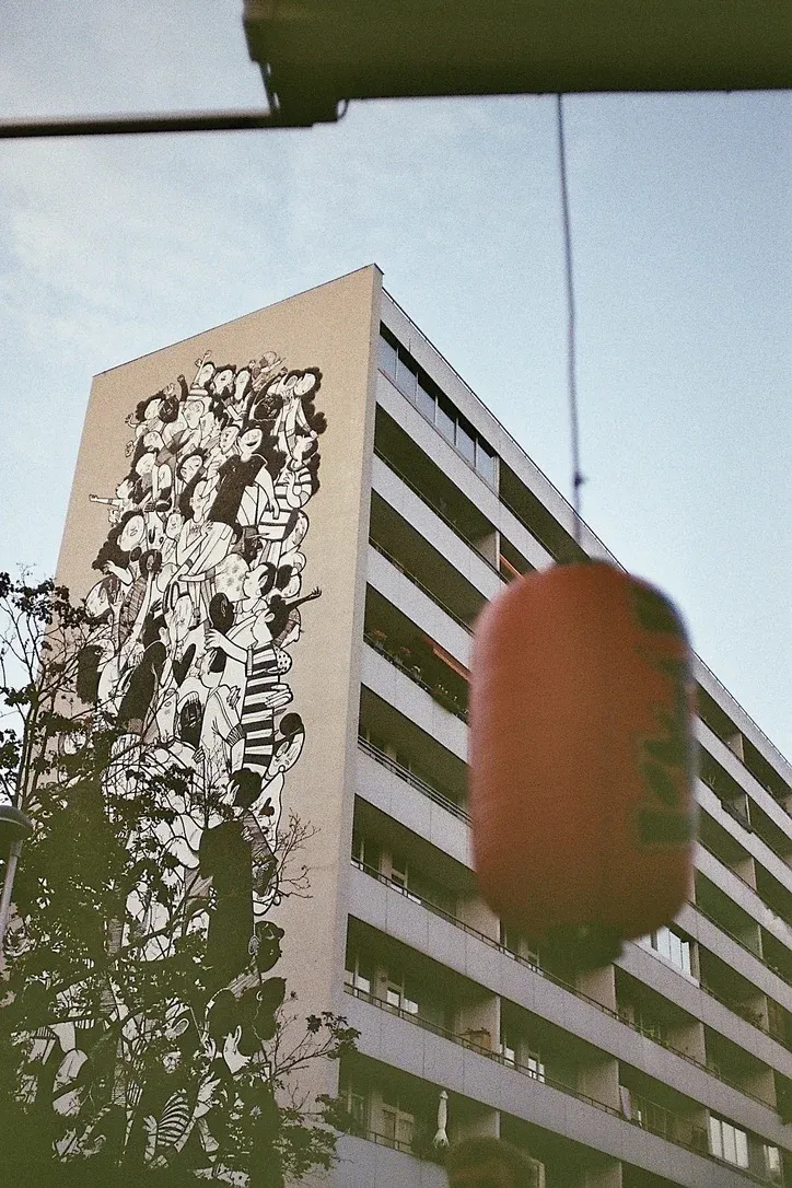 High-rise residential building with a modern black-and-white mural behind a traditional Japanese lantern